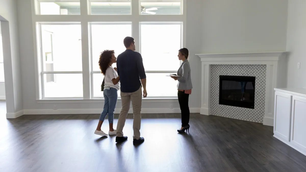couple speaking with a realtor inside an empty house